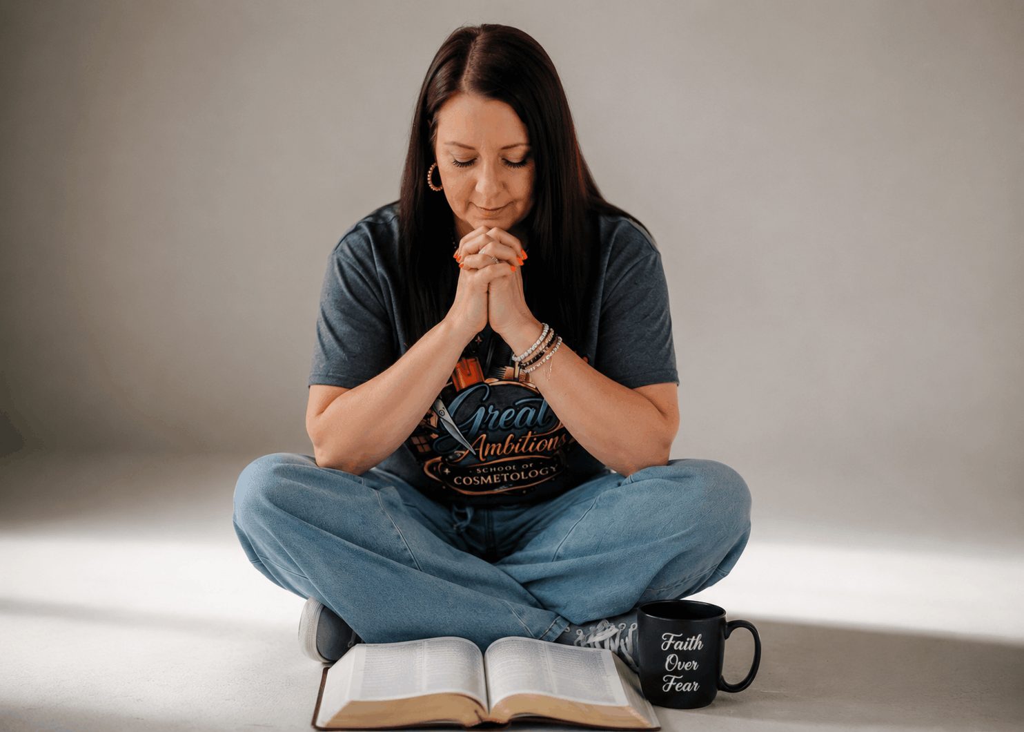 Amanda Morris in prayer beside a Faith Over Fear mug and an open book